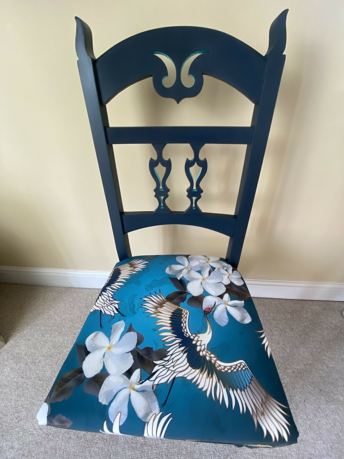 A blue painted high back vintage chair reupholstered in a turquoise blue crane and flower fabric