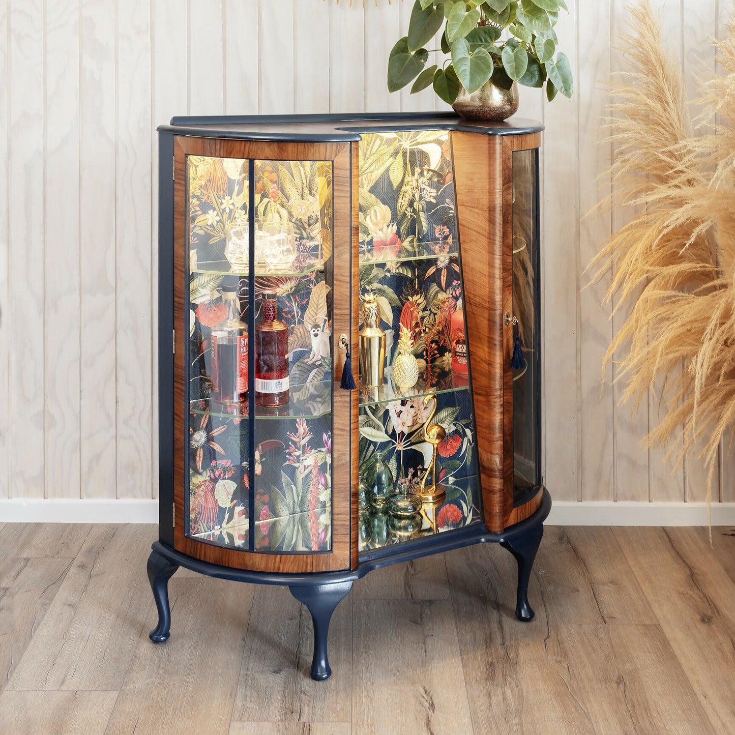 Professionally refinished Art Deco drinks cabinet, distinguished by its unique design and tropical jungle fabric. Sold, commission available.