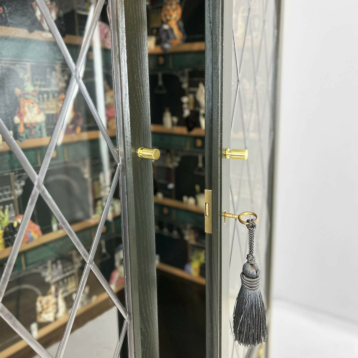 Antique style display cabinet with animals in the bar, painted green and gold guilded with glass shelves