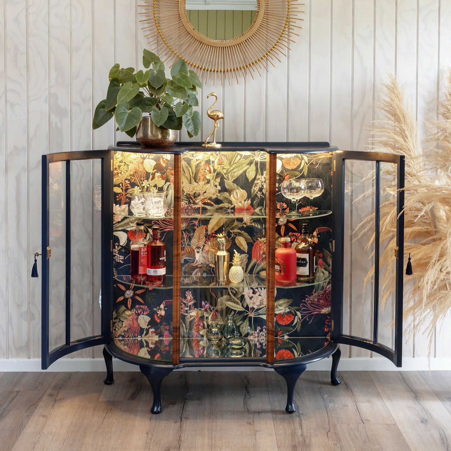 Professionally refinished Art Deco drinks cabinet, distinguished by its unique design and tropical jungle fabric. Sold, commission available.