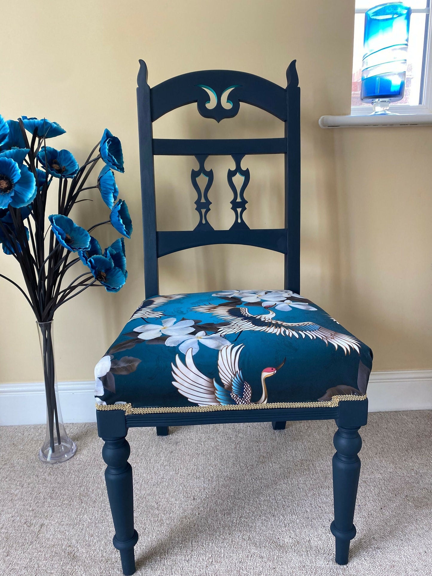 A blue painted high back vintage chair reupholstered in a turquoise blue crane and flower fabric