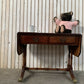 Antique drop-leaf Pembroke table with a leather top and brass claw feet.