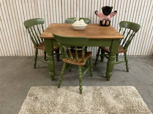 A vintage pine dining table with four chairs in a green and brown and a Drawer.