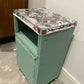 Green painted glass topped cabinet. Beautiful fabric accent top.