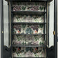 Interior shelves with botanical and bird patterned backing inside display cabinet