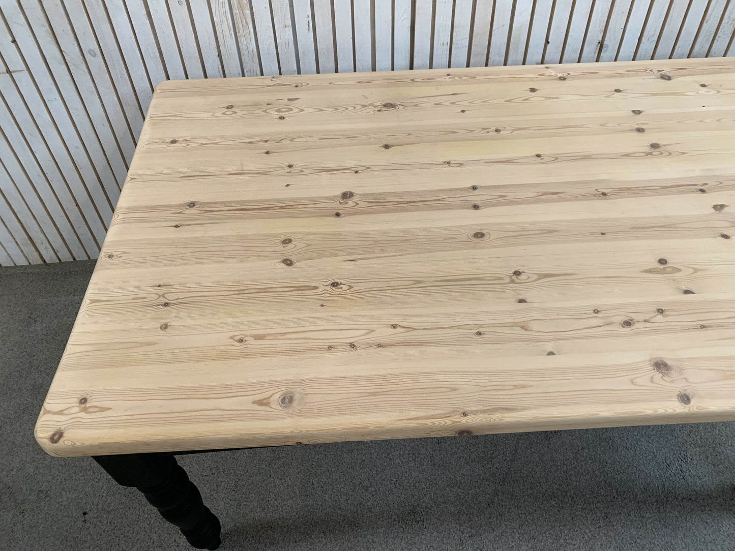 Pine dining table with a black base and a lacquered pine top.