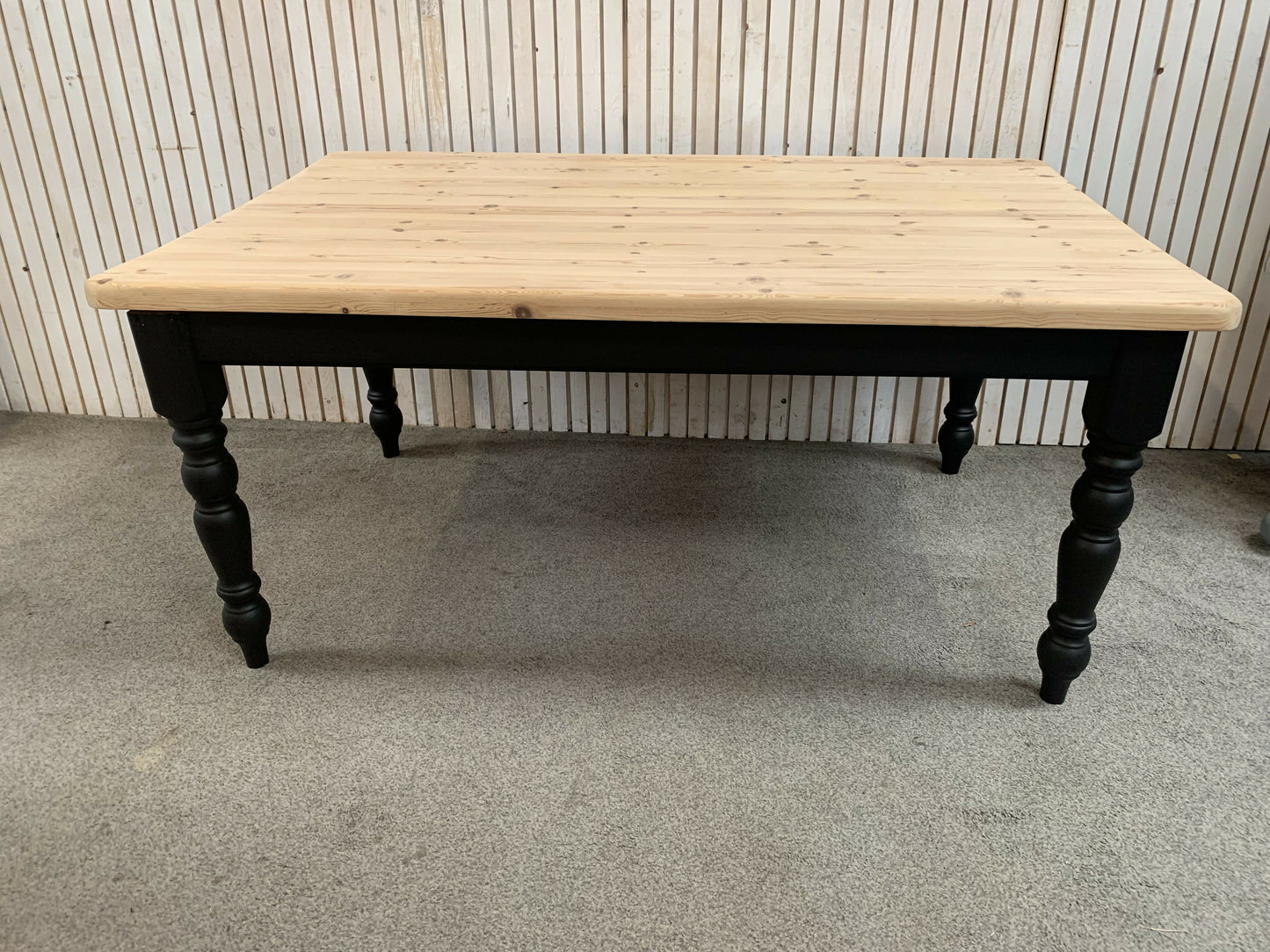 Pine dining table with a black base and a lacquered pine top.