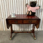 Antique drop-leaf Pembroke table with a leather top and brass claw feet.