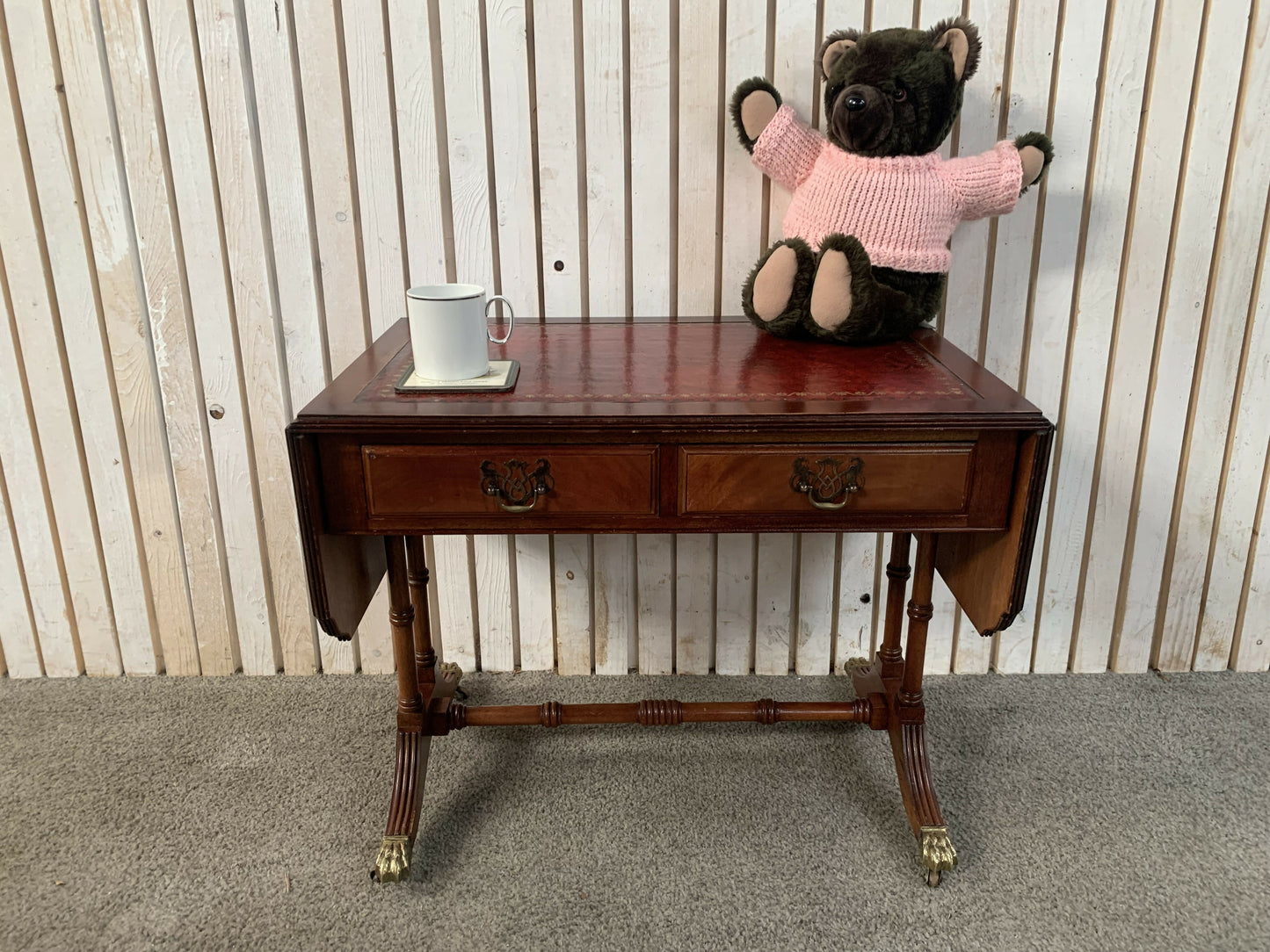 Antique drop-leaf Pembroke table with a leather top and brass claw feet.