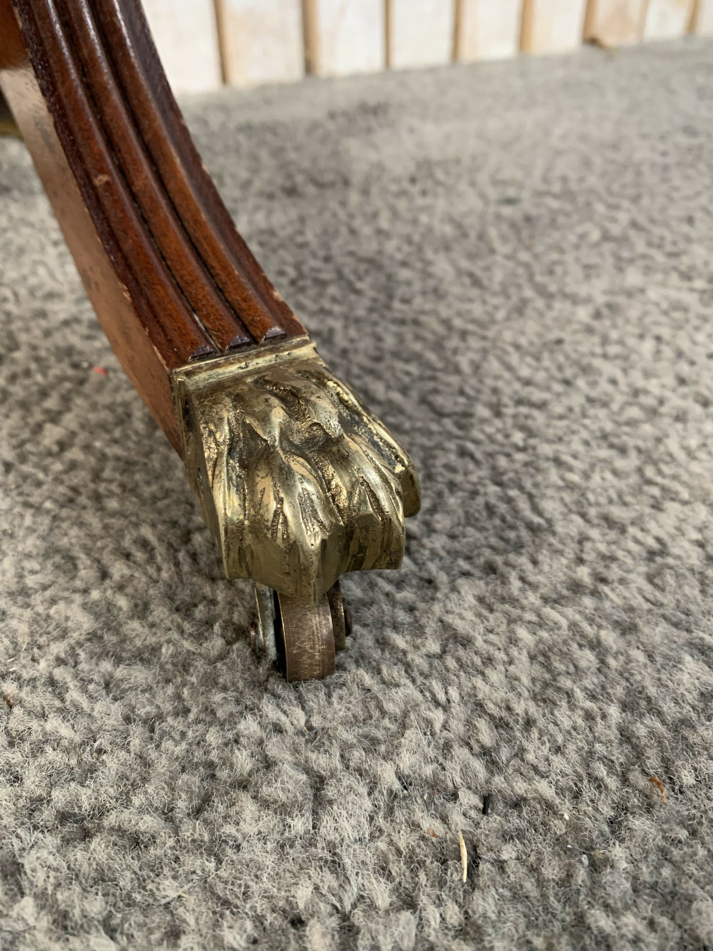 Antique drop-leaf Pembroke table with a leather top and brass claw feet.