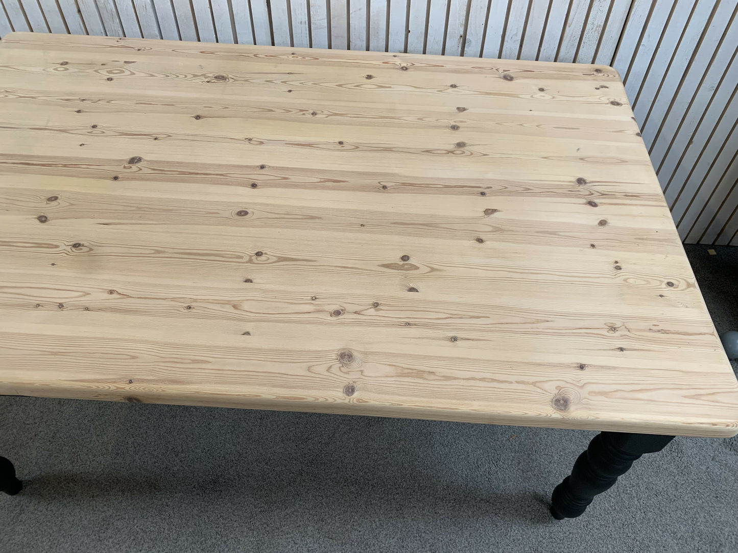 Pine dining table with a black base and a lacquered pine top.