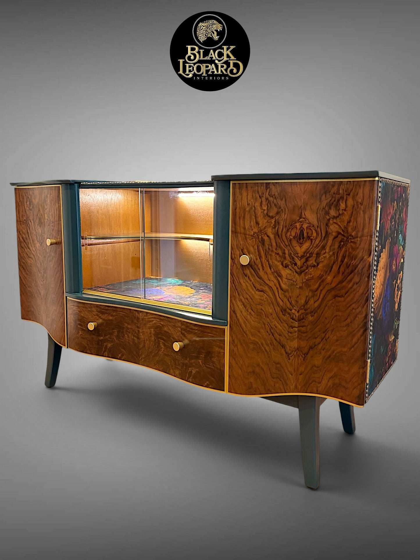 Professionally refinished vintage art deco sideboard with burr walnut, illuminated glass display and floral side panels by Black Leopard Interiors. Luxury bespoke furniture refinishing and restoration handcrafted handpainted UK