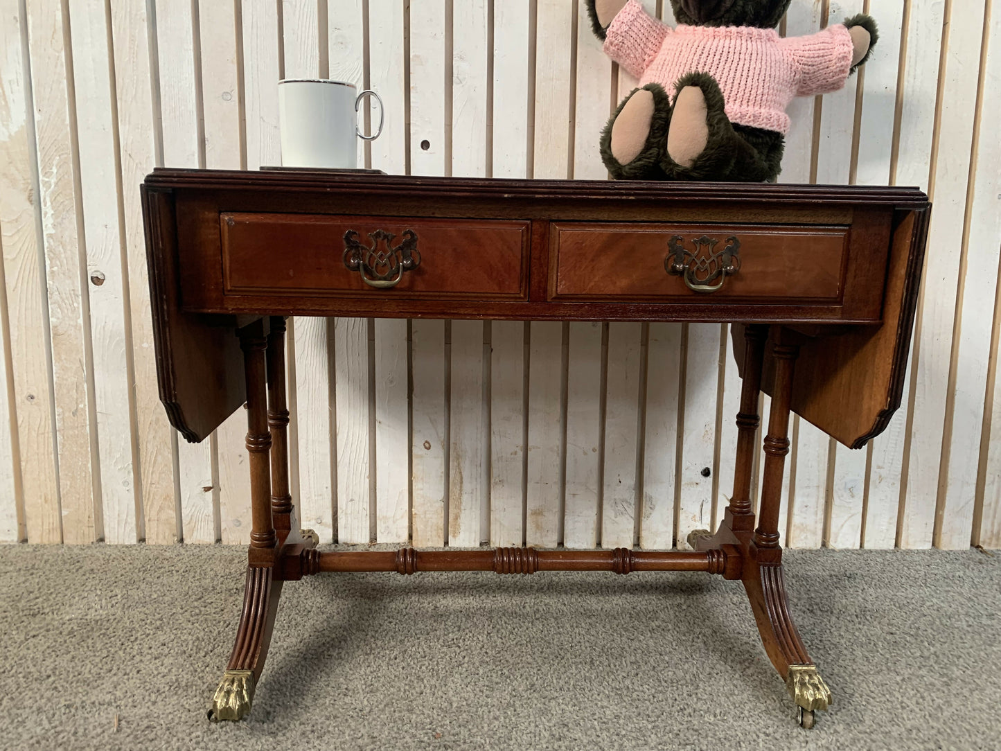 Antique drop-leaf Pembroke table with a leather top and brass claw feet.