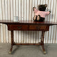 Antique drop-leaf Pembroke table with a leather top and brass claw feet.