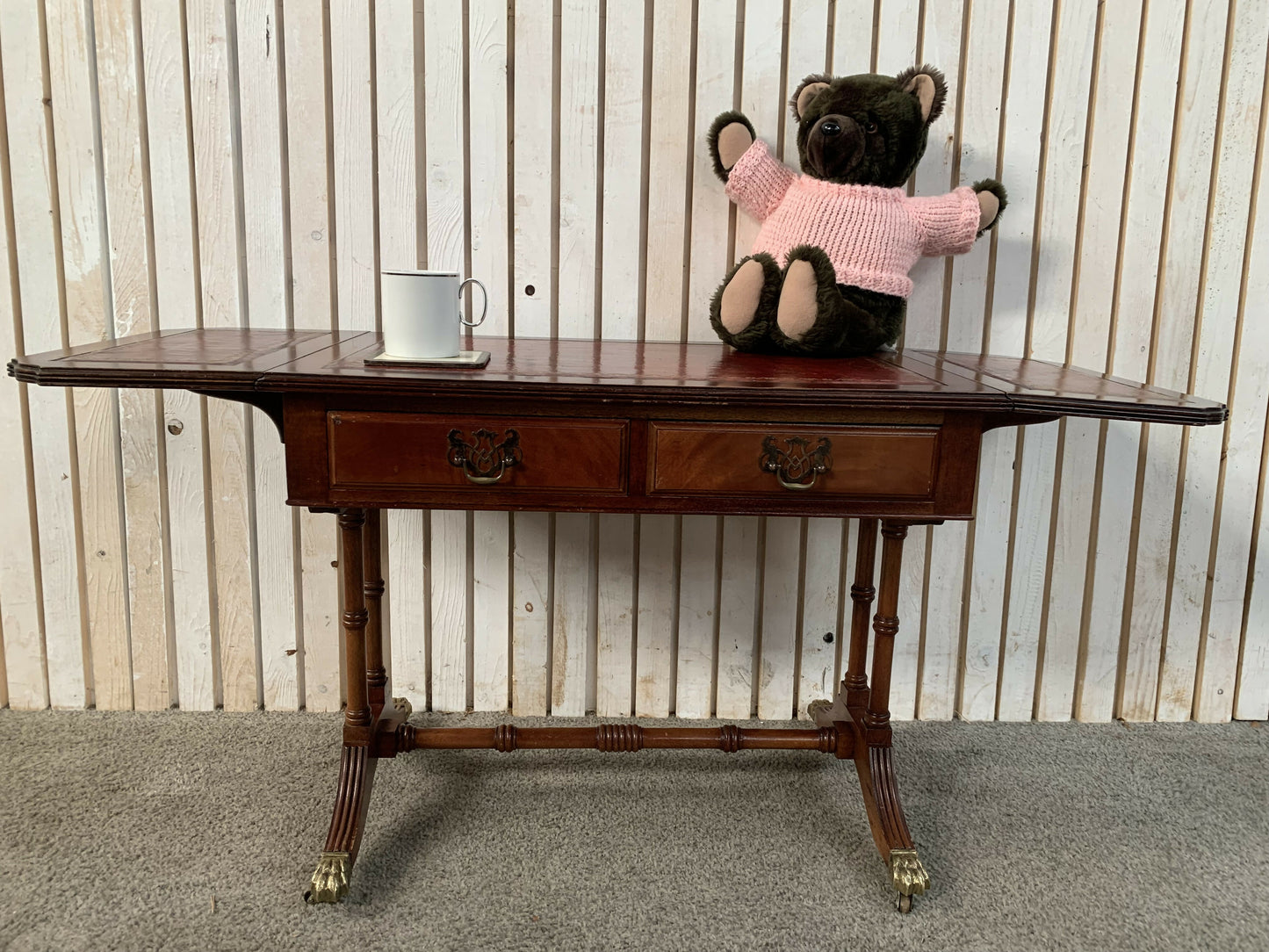 Antique drop-leaf Pembroke table with a leather top and brass claw feet.
